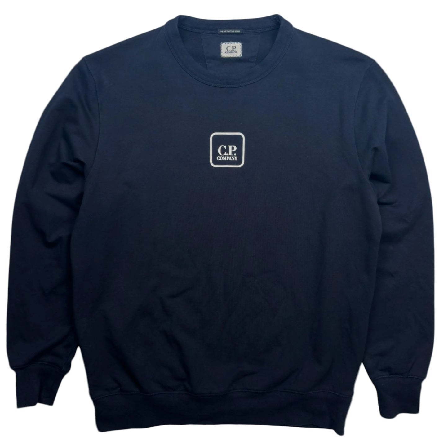 A navy blue crewneck sweatshirt with a small white square logo on the left chest that reads 'CP COMPANY'. The brand 'CP' is also visible on the inner neck label.